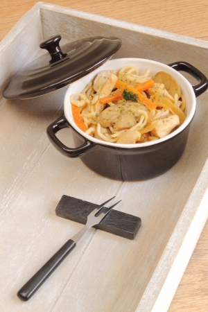 Black cooking pot with chicken noodlesの写真素材