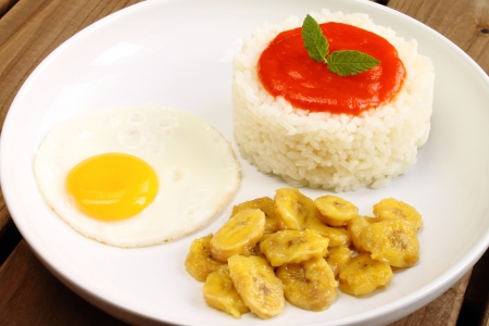 Rice Cuban style, with cooked rice, tomato sauce, fried egg and fried bananaの写真素材