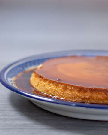 Neapolitan flan in a blue plate, with a little liquid caramel around itの写真素材