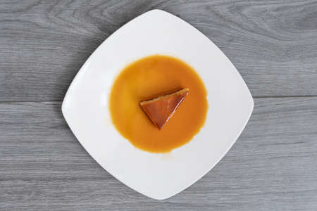 triangular slice of a Neapolitan custard on a white plate lying on a light gray wooden tableの写真素材
