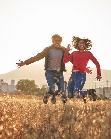 Man jumping in jeans, blue jacket, white t-shirt, with glasses together with a woman in red sweater...