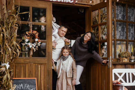 A beautiful family with two children stand at the door of their house.