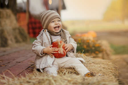 Happy baby sitting on the hay and laughing.