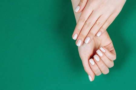 christmas white manicure on a green background top view.の写真素材