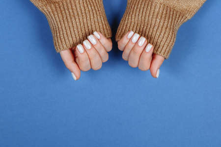 christmas white manicure on a blue background top view.の写真素材