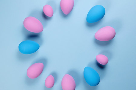 Pink Easter eggs on a blue background with ribbons and feathers with a place for textの写真素材