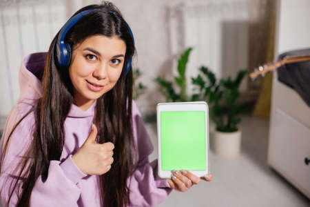 The girl smiles and holds a tablet in her hands.