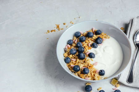 Yogurt with muesli and fresh blueberries on a gray background, perfect breakfast.の写真素材