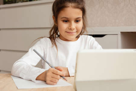 The girl is sitting at the table and is undergoing online trening.の写真素材