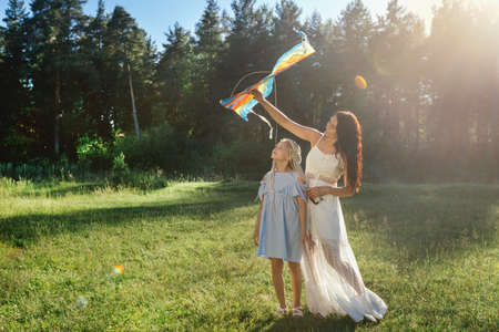 Mom and daughter fly a kite at sunset.の写真素材