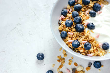 Yogurt with muesli and fresh blueberries on a gray background, perfect breakfast.