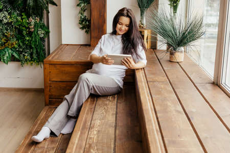 A pregnant girl communicates on a tablet.の写真素材