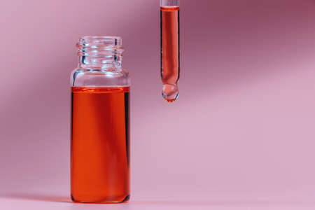 Pipette with a glass bottle on a pink background and with oil.の写真素材