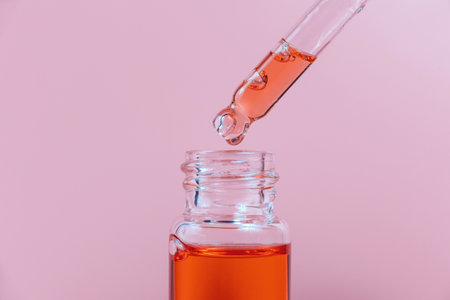 Pipette with a glass bottle on a pink background and with oil.の写真素材