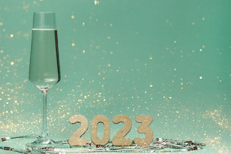 A glass of champagne and numbers of the year on a background of sequins