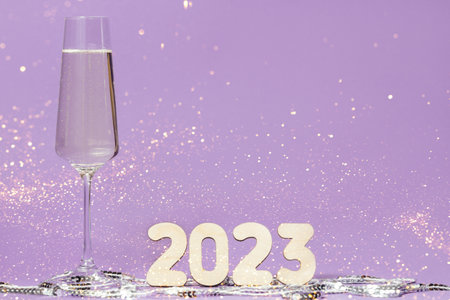 A glass of champagne and numbers of the year on a background of sequins
