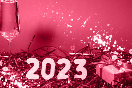 A glass of champagne and the numbers of the year on a magenta background and sparkles. trendy color...