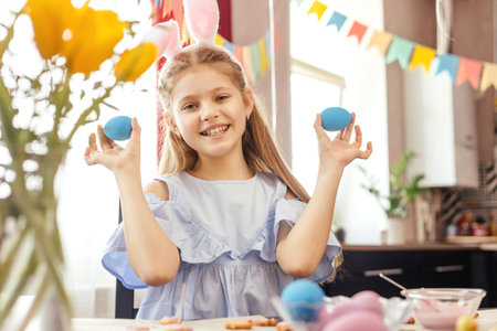 Cheerful little girl plays with Easter eggs.