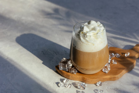 Coffee latte on a gray table in bright sunlight and free space. Cold summer coffee with ice. gray background.の写真素材