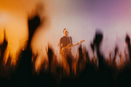 Energetic rock concert with male guitarist on stage amid vibrant lights.の素材