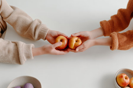 Two people sharing apples on white table.の素材