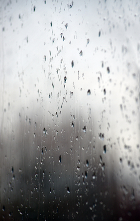 Rain drops on window glasses surface with bokeh background.の写真素材