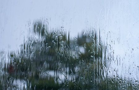 Rain drops on glass surface with bokeh background.