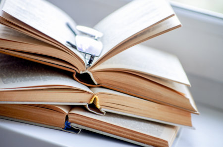 Open book on a window sill, illuminated by sunlight.の写真素材