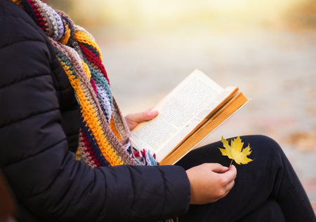 Girl is sitting on bench and reading book.の写真素材