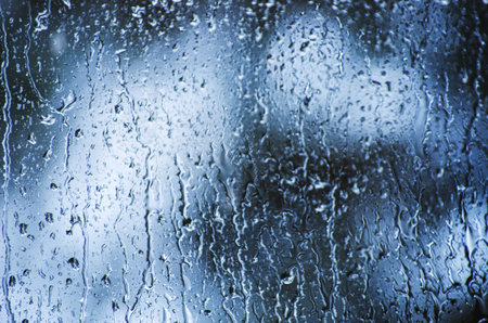 Rain drops on glass surface with bokeh background.