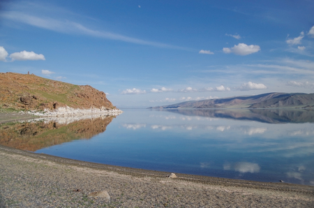 Summer landscape. Mongolian Altai. Colorful blue sky with clouds reflected in a crystal clear cold water of the mountain freshwater lake. Elevation is at 2080 meters high. Nature and travel. Mongolia, lake Tolboの写真素材