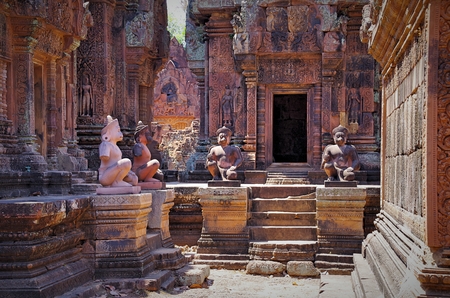 Monkeys protect an entrance to a sanctuary. Banteay Srei - pink temple, citadel of the women, or citadel of beauty. Buildings of the temple are tiny and beautifully decorated with intricate patterns and carved bas-reliefs. Devatas and Dvarapalas on facadeのeditorial素材