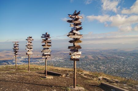 Pointers on the top of mountain on background of evening sky. Wooden signs of direction with cities name on Mount Mashuk. Russia, Stavropol Krai, Pyatigorskの写真素材