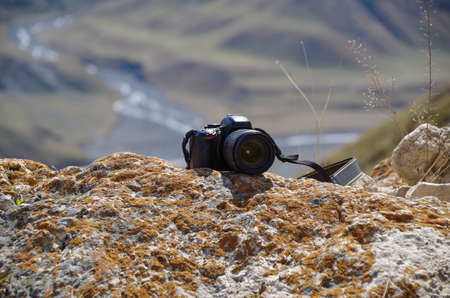 Modern camera on rock in the sunny day with mountain valley view background. Russia, North Caucasus, Dagestan, Dokuzparinsky District, Kurushの写真素材