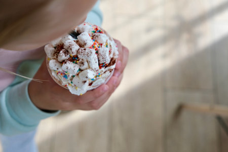 The girl is holding a paper cup with cocoa and marshmallows. Delicious children's drinkの写真素材