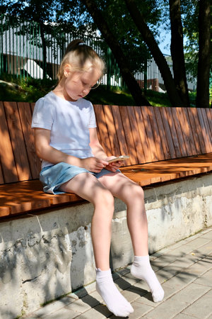 A child uses a smartphone on the street. Gadgets and kids. Use a smartphone. Use a smartphoneの写真素材