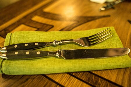 fork and knife lie on a napkin on the kitchen tableの写真素材
