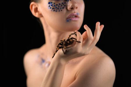 a girl and a large spider creeps on it during shooting