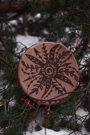 shaman tambourine lies on snow and spruce branches