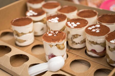 tiramisu cake is in a cardboard box and in plastic transparent cups