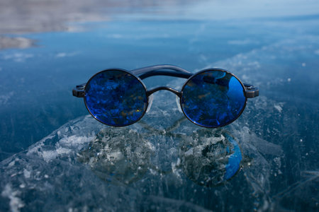 blue glasses lie on transparent iceの写真素材