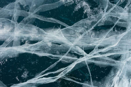 thin cracks of ice in a transparent lakeの写真素材