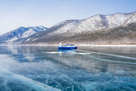 transparent ice on Lake Baikal against the background of mountainsの写真素材