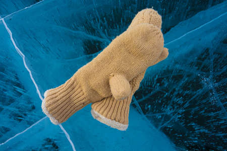 two warm mittens lie on transparent iceの写真素材