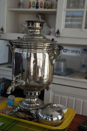 a large metal samovar of silver color stands on a tray