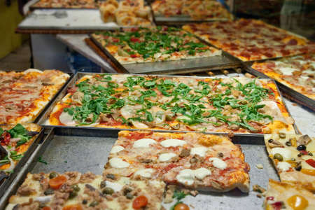 Multiple types of pizza in pans in pizzeria.の写真素材