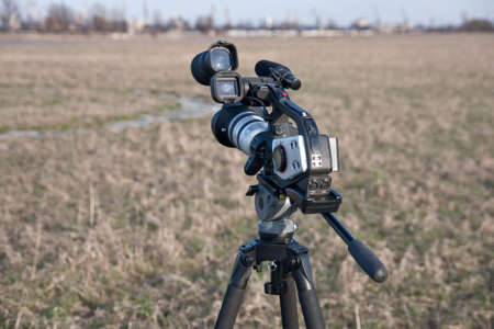 Video camera on tripod in grass field.の写真素材