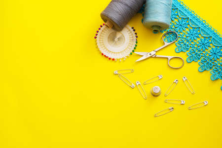 Multi-colored reels with sewing threads, meter tape, scissors on a bright background. Flat layの写真素材