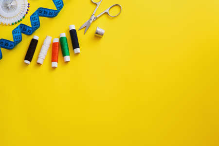 Multi-colored reels with sewing threads, meter tape, scissors on a bright background. Flat layの写真素材