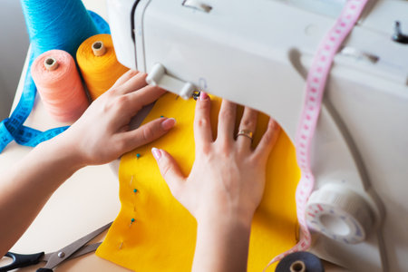 Seamstress's workplace. Professional sewing machine at work. Sewing machine sews bright textiles,...